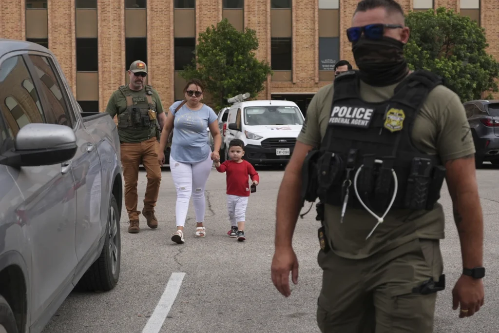 Federal agents escort  a woman and her children 
