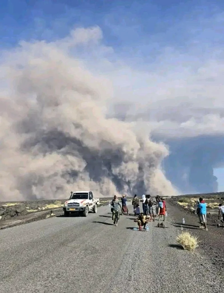 People watch ash billows from an eruption of the long-dormant Hayli Gubbi Volcano in Ethiopia's Afar region on November 23, 2025