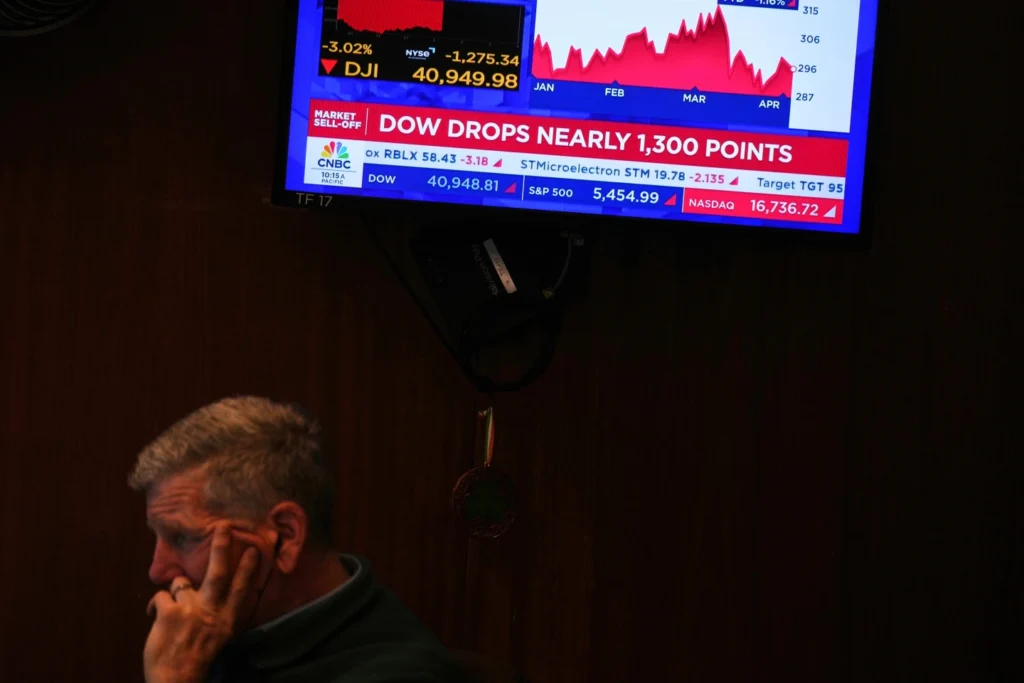 A screen displays financial news as traders work on the floor at the New York Stock Exchange in New York