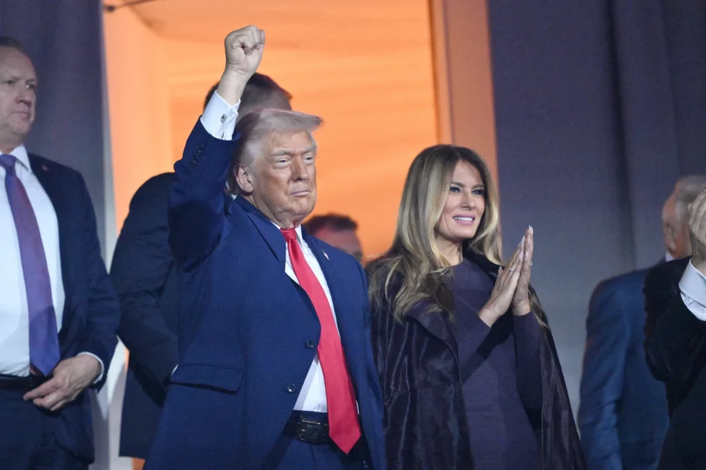 President Donald Trump pumps his fist alongside with first lady Melania Trump reach after the draw for the 2026 soccer World Cup at the Kennedy Center in Washington