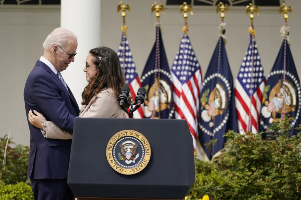 Former President Joe Biden hugs Mia Tretta, a survivor of the Saugus Hight School shooting in Santa Clarita, Calif., after she spoke in the Rose Garden of the White House in Washington, April 11, 2022
