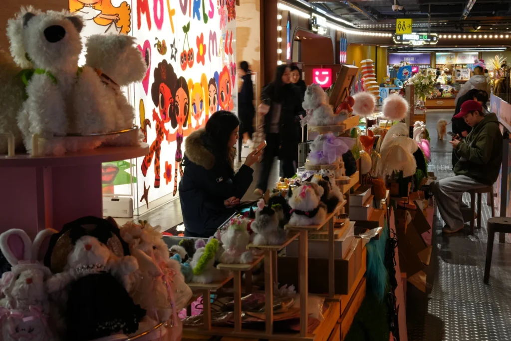 Shoppers walk by vendors waiting for customers at their stores inside a shopping mall, in Beijing
