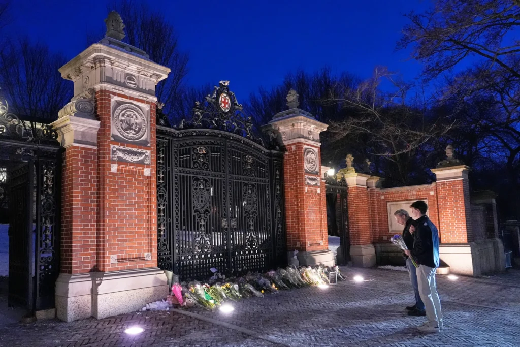 Visitors pause at a makeshift memorial for the victims of Saturday’s shooting, at the Van Wickle Gate at Brown University, Monday, Dec. 15, 2025, in Providence, R.I.