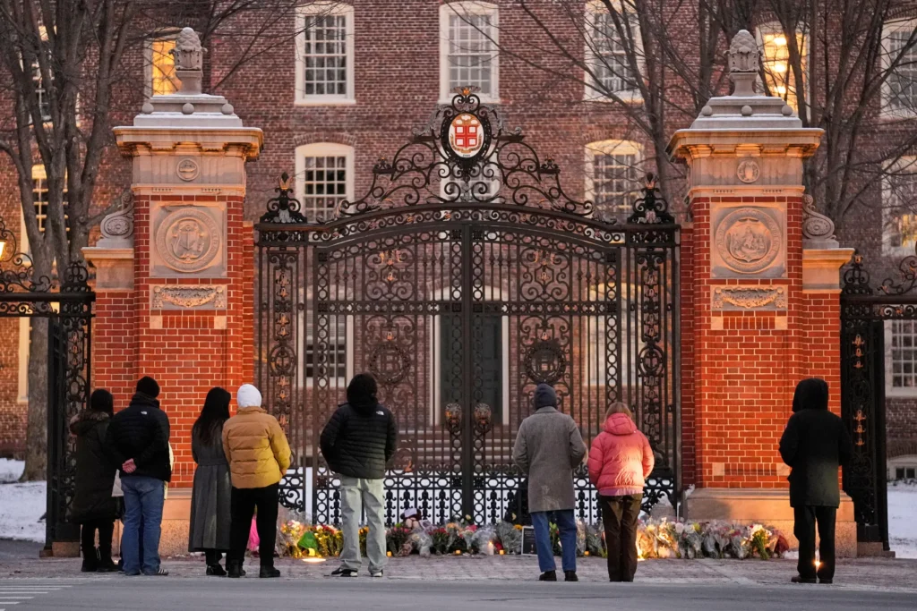 Visitors pause at a makeshift memorial for the victims of Saturday’s shooting, at the Van Wickle Gate at Brown University, Monday, Dec. 15, 2025, in Providence, R.I. 